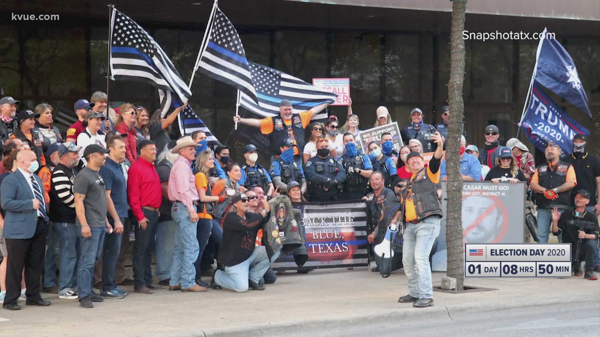 Austin police officers have been criticized for posing with the group after some members in the crowd were seen displaying a "white power" hand gesture.